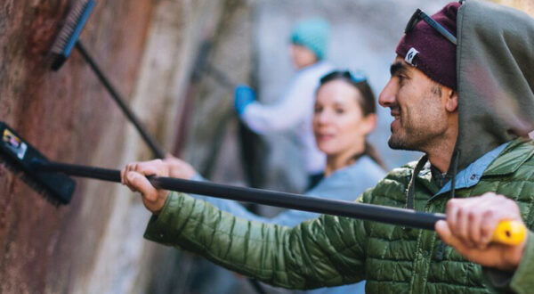 Climber brushing rock clean on climbing wall | Access Fund