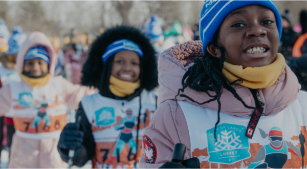 A line of Black children smiling on skis during a Share Winter Foundation event