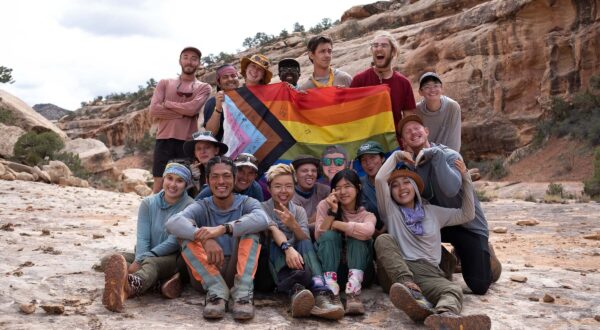 A group of people in the desert holding a rainbow Pride flag